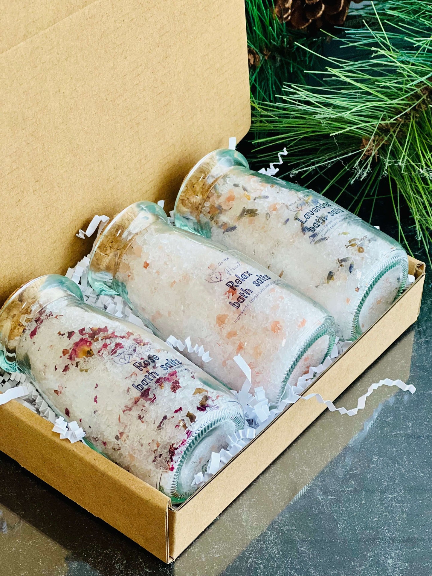 Handcrafted bath salts in glass jars with cork stoppers, presented in a gift box with decorative filler.