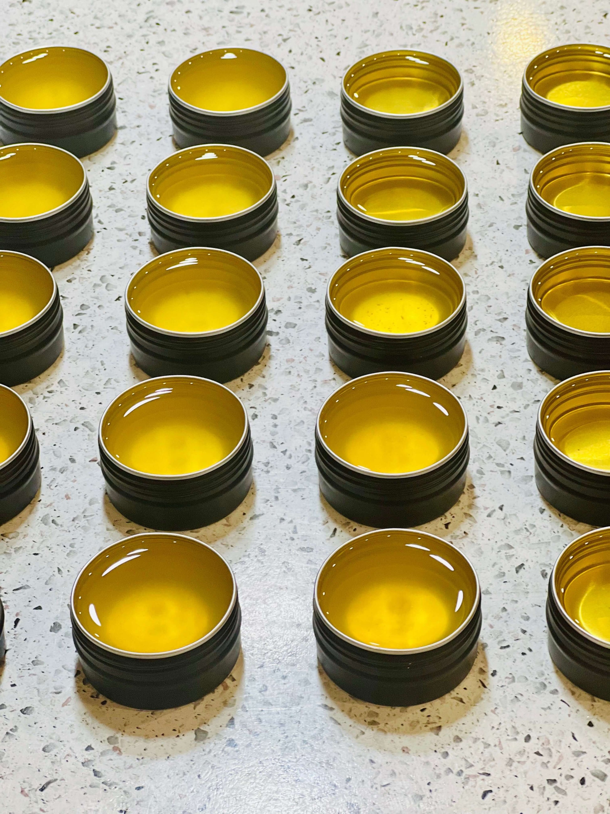 Handcrafted organic beef tallow balm jars arranged neatly on a countertop, showcasing rich golden color.