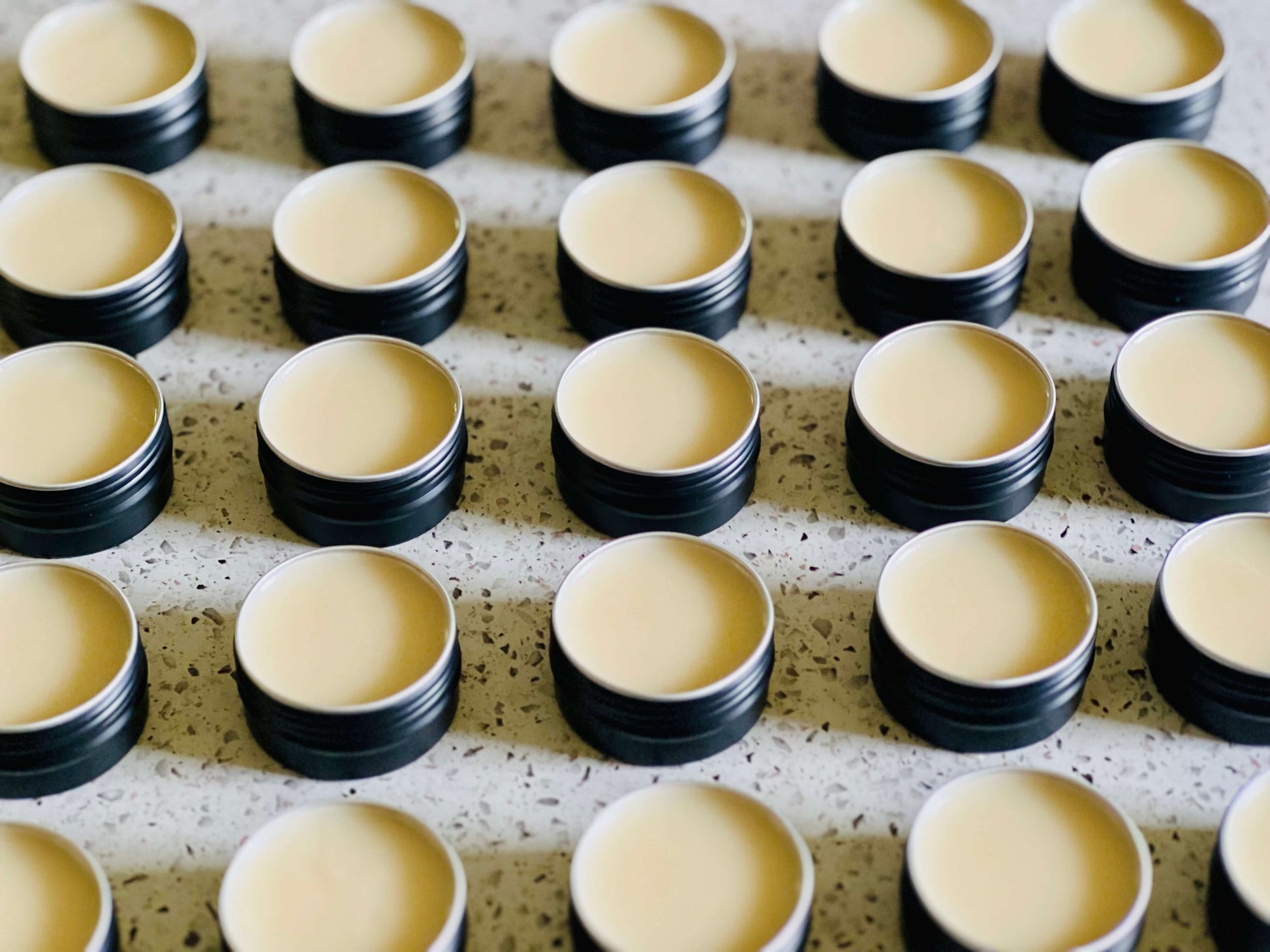 Rows of small containers filled with organic beef tallow balm for skin nourishment and hydration.