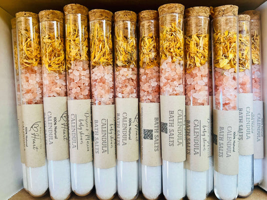 Natural calendula bath salts in glass tubes with cork lids, featuring pink Himalayan salt and dried flowers.