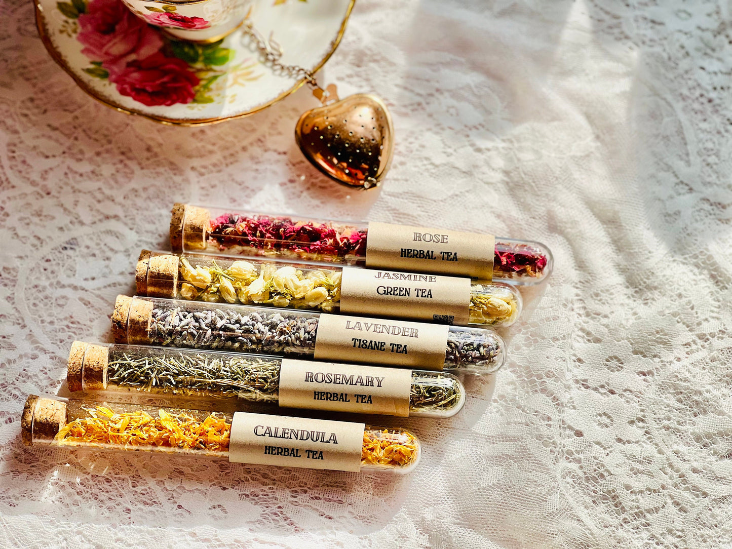 May include: Six plastic test tubes with cork stoppers filled with various dried herbs and flowers. Each tube has a brown paper label with the name of the herb and the words &#39;Herbal Tea&#39; printed on it. The labels read: &#39;Rose Herbal Tea&#39;, &#39;Jasmine Green Tea&#39;, &#39;Lavender Tisane Tea&#39;, &#39;Rosemary Herbal Tea&#39;, &#39;Calendula Herbal Tea&#39;.