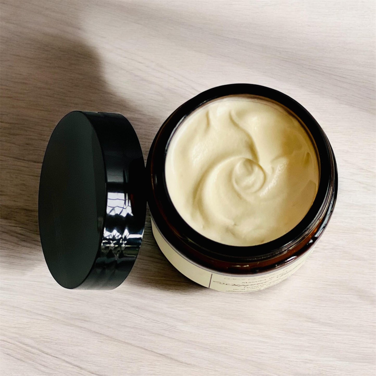 The jar has the lid off showing the smooth texture of the whipped tallow.